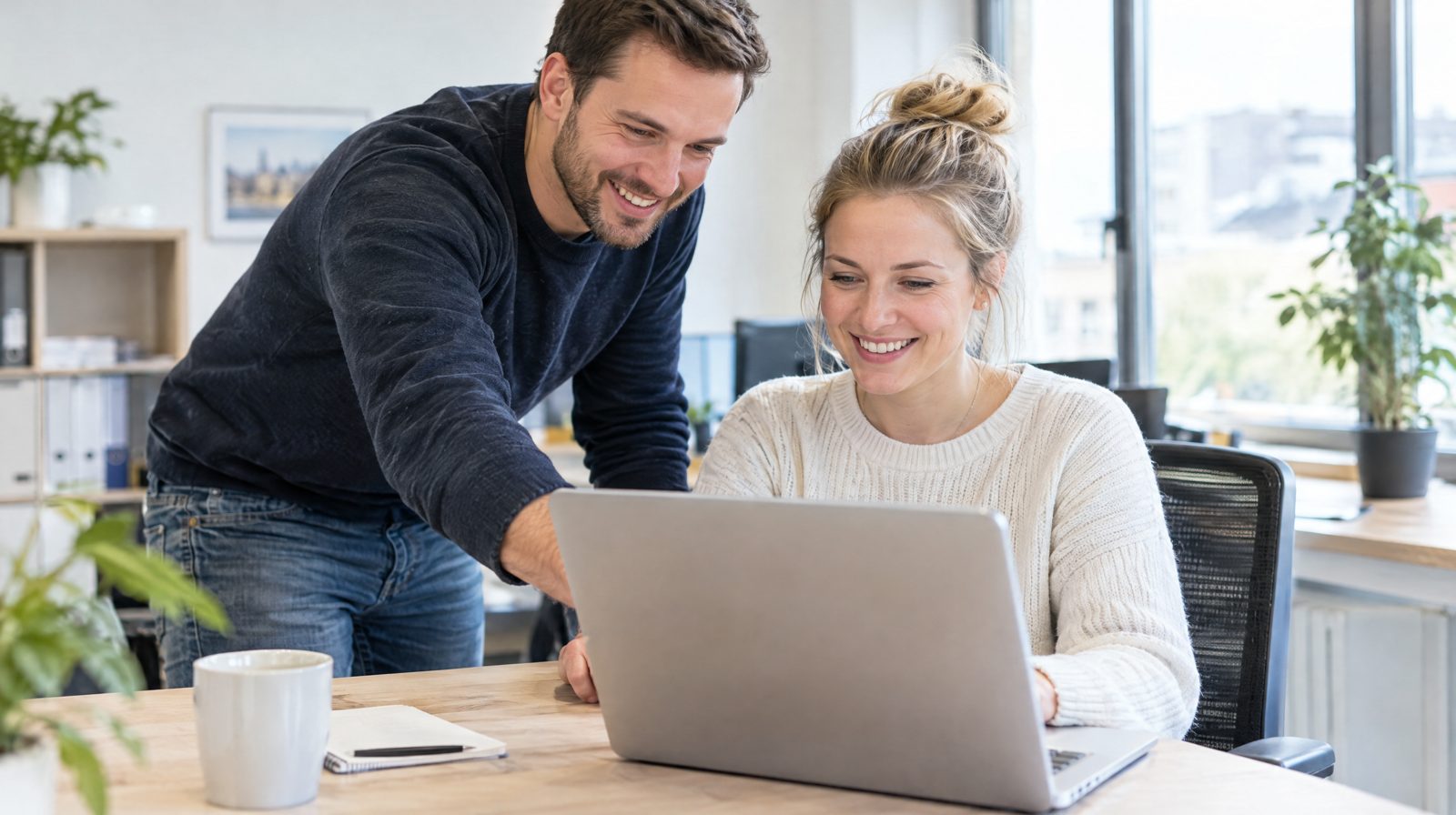 IT-Support im Büro: IT-Betreuer hilft einer Mitarbeiterin direkt am Arbeitsplatz bei einem Laptop-Problem